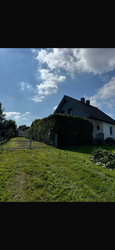 Ein Haus mit Garten unter einem klaren Himmel und einigen Wolken.